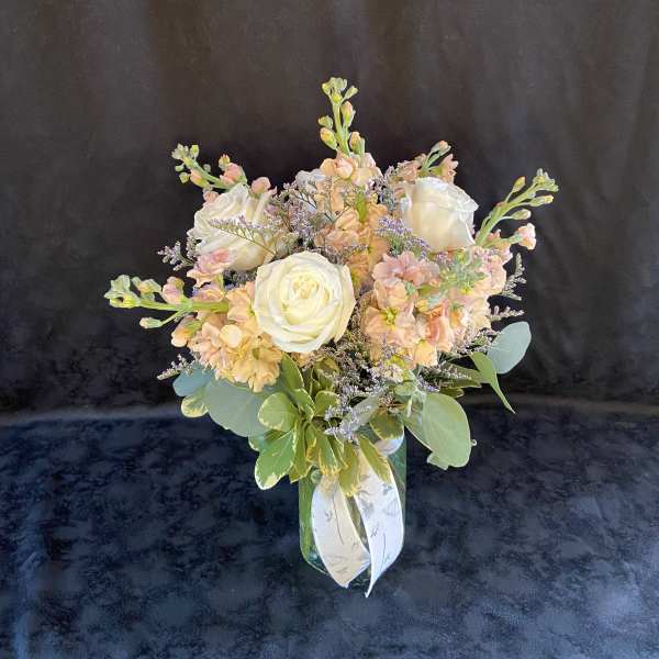 Bouquet of white roses and peach flowers in a glass vase