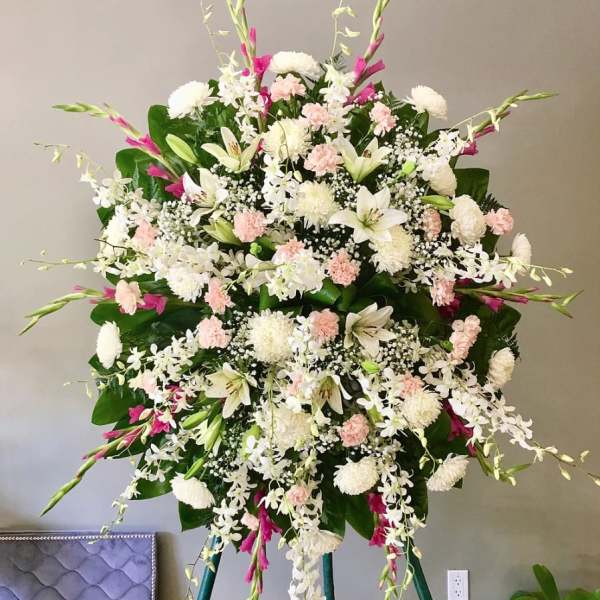 Large standing spray of white and pale pink flowers on an easel