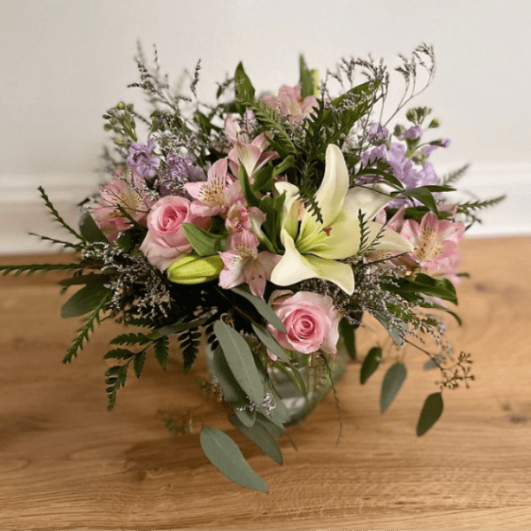 Pink roses and lilies arranged in a glass vase