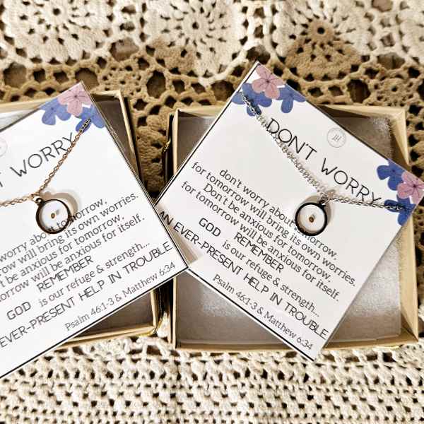 Two gift boxes with scripture cards and necklaces on a crocheted background
