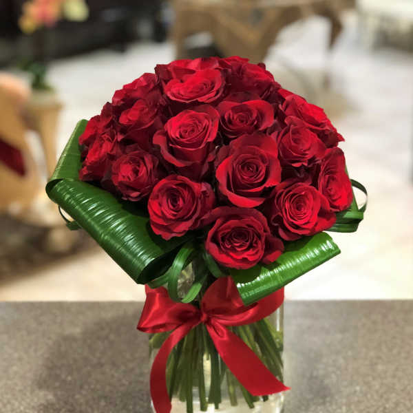 Bouquet of red roses in a glass vase with a red ribbon