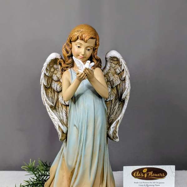 Angel figurine holding a white dove beside a florist card