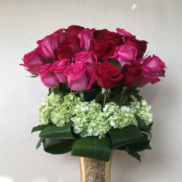 Bouquet of pink and red roses in a gold vase with white hydrangeas