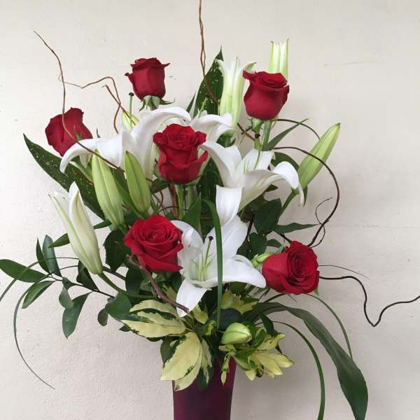 Red roses and white lilies in a tall purple vase