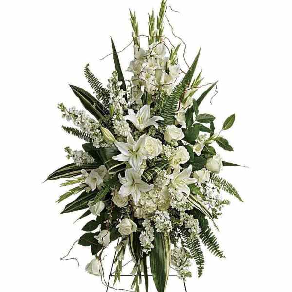 White floral standing spray with lilies and roses on a metal easel