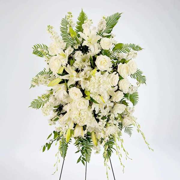 White floral standing spray with roses and lilies on a stand