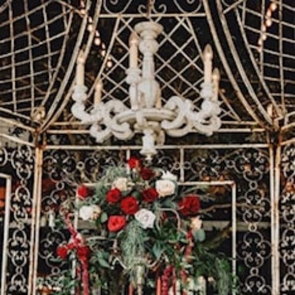 Red and white rose centerpiece on a formal table beneath a chandelier