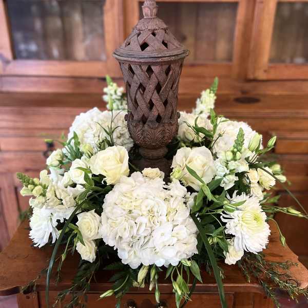 White floral arrangement around a decorative lantern centerpiece
