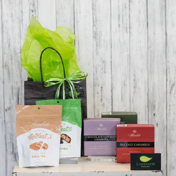 Gift bag with assorted candy boxes and treats on a wooden surface
