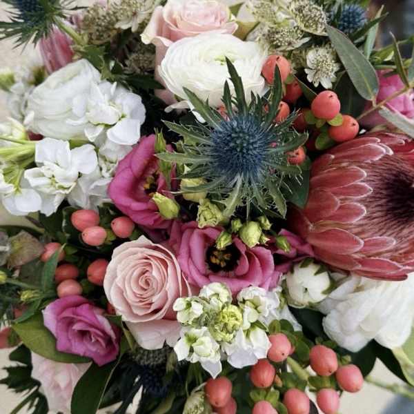 Mixed bouquet with pink and white flowers and a blue thistle bloom