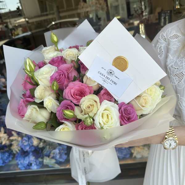 Bouquet of pink and white roses wrapped in white paper
