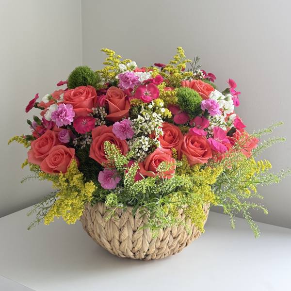 Pink roses and mixed flowers in a woven basket