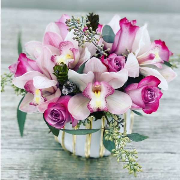 Pink orchids and roses arranged in a white vase