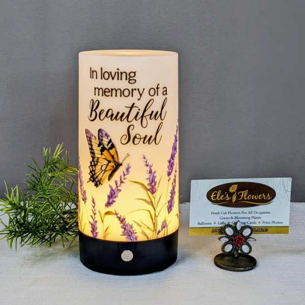 Memorial candle with butterfly and lavender design beside a small card holder
