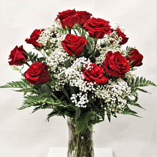 Arrangement of red roses with white filler flowers in a clear glass vase