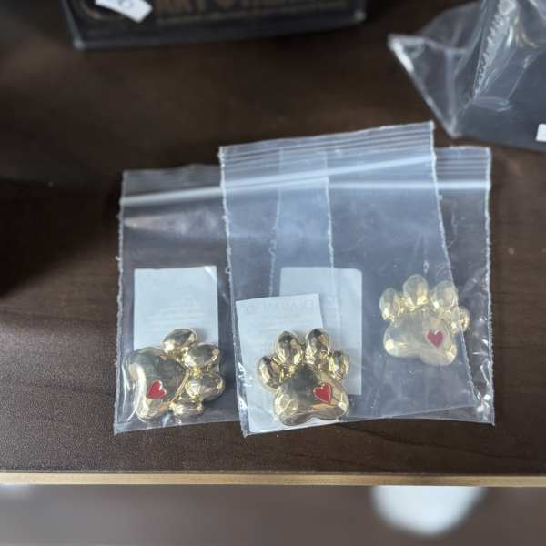 Three gold paw-print charms in clear plastic bags
