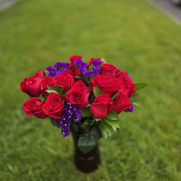 Bouquet of red roses with purple filler flowers in a vase