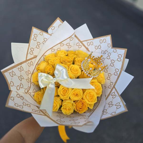 Bouquet of yellow roses wrapped in patterned paper with a satin ribbon