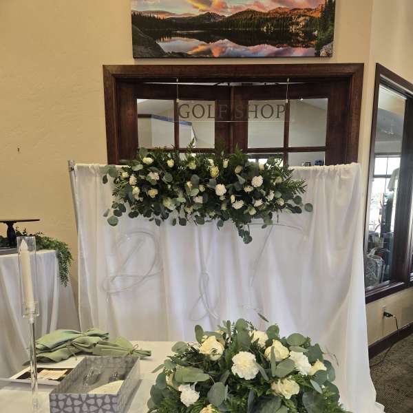 White floral arrangements with greenery on a draped table and backdrop