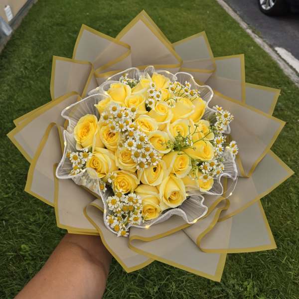 Yellow rose bouquet with small white daisies wrapped in beige paper