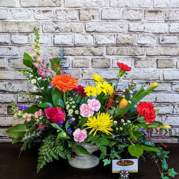 Colorful mixed flower arrangement in a white pedestal vase