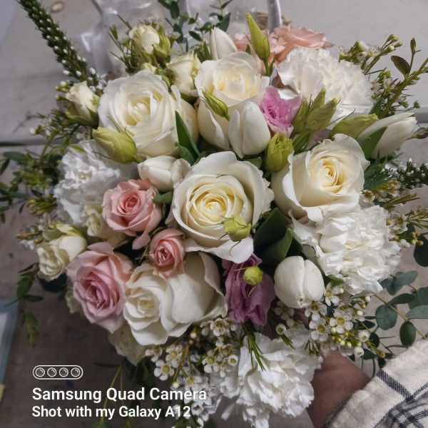 Handheld bouquet of white and blush roses with tulips and white filler flowers