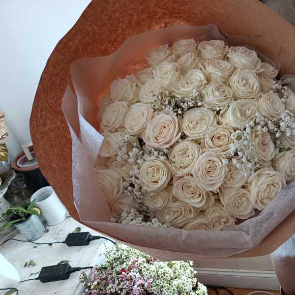 Large bouquet of cream roses wrapped in brown paper
