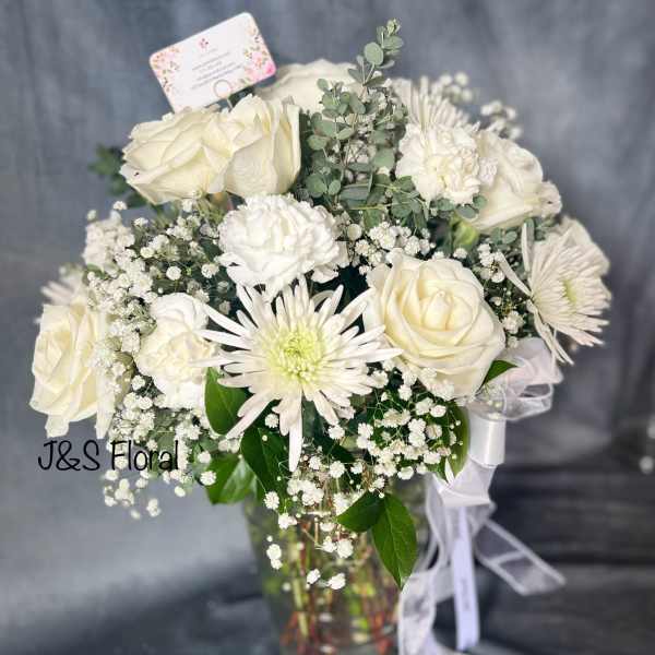White roses and chrysanthemums in a glass vase with baby's breath