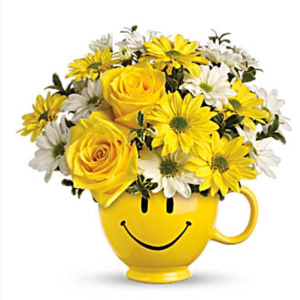 Yellow and white flowers arranged in a smiley-face mug