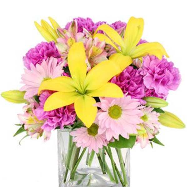 Pink and yellow mixed flowers arranged in a clear glass vase