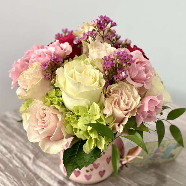 Pink and cream rose bouquet in a heart-patterned mug