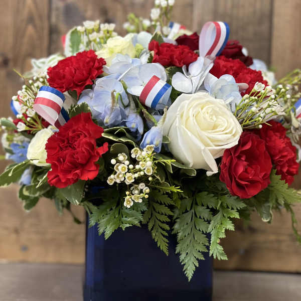 Red and white roses with blue flowers in a dark vase
