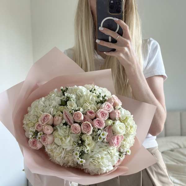 Large bouquet of pale pink roses and white hydrangeas wrapped in blush paper