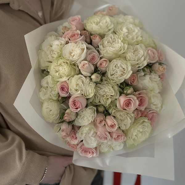 Bouquet of pale pink and white roses wrapped in white paper