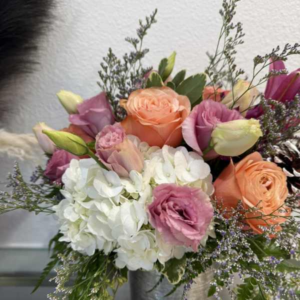 Mixed bouquet of pink and peach roses with white hydrangea in a metal vase