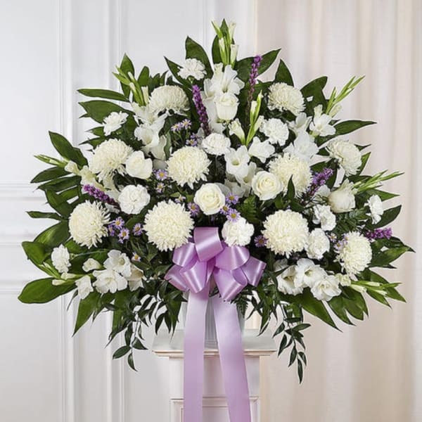 White floral standing spray with a lavender ribbon on a pedestal