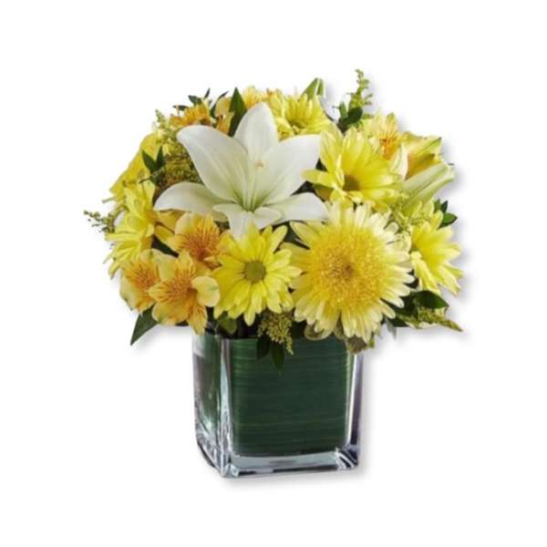 Yellow flowers with a white lily in a square glass vase