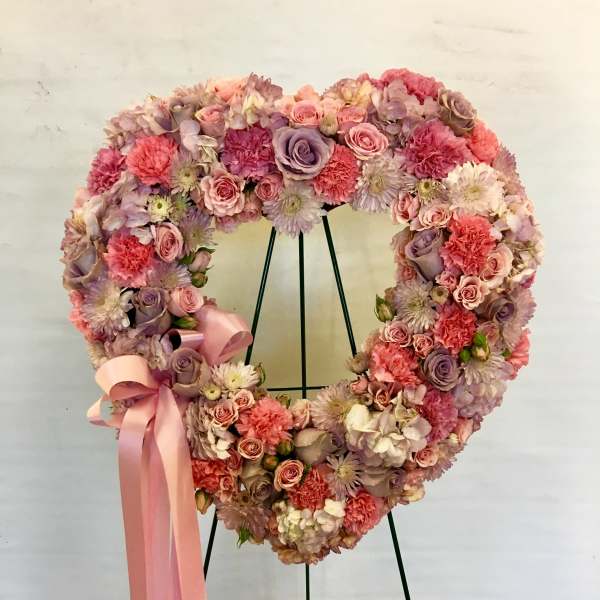 Heart-shaped floral wreath with pink and lavender blooms and a pink ribbon
