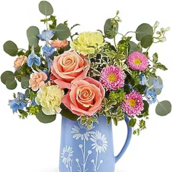 Mixed bouquet in a blue floral pitcher with pink roses and colorful blooms