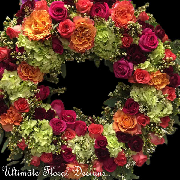 Circular floral wreath with roses and hydrangeas in pink, orange, and green