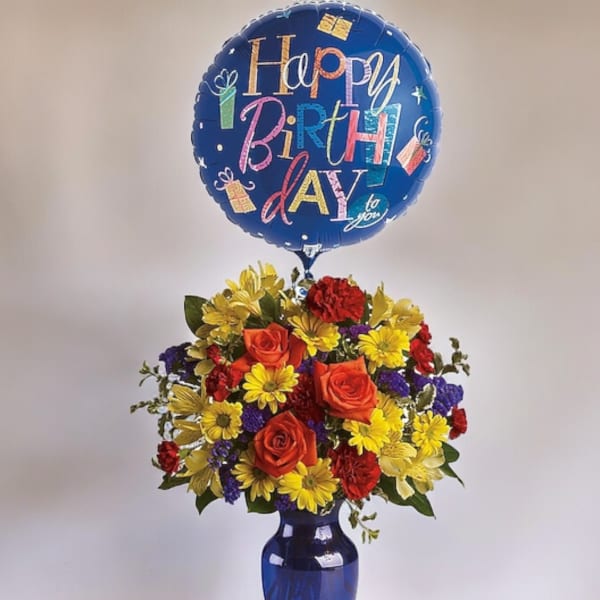 Birthday balloon above a colorful flower arrangement in a blue vase