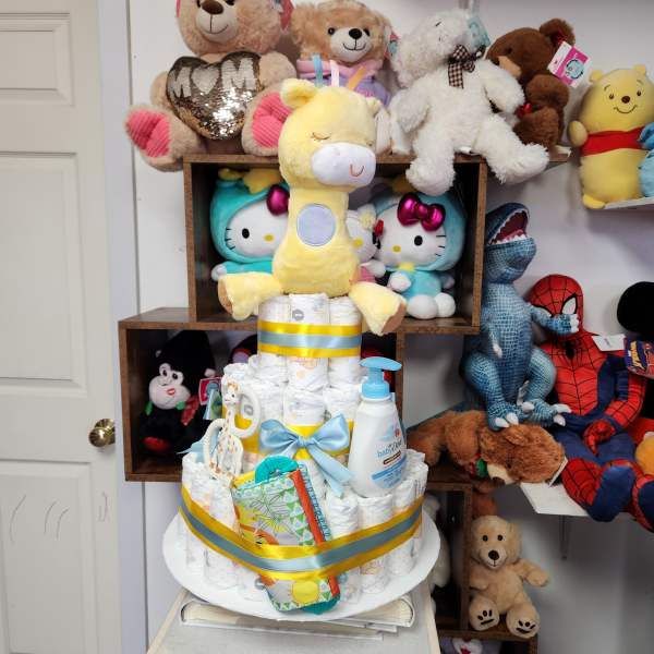 Diaper cake topped with a yellow plush giraffe and baby items
