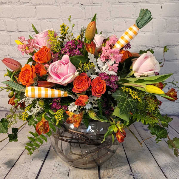 Mixed bouquet of roses and lilies in a glass vase with carrot decorations