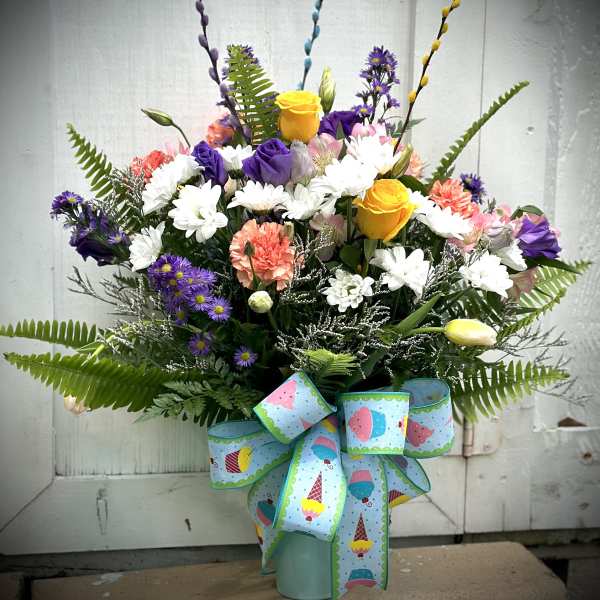 Mixed bouquet in a blue vase with a large patterned ribbon