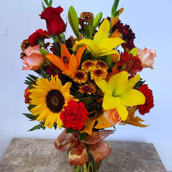 Mixed bouquet in a glass vase with sunflowers, lilies, roses, and carnations
