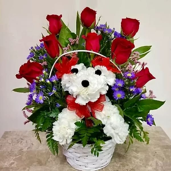 Basket arrangement of red roses, white daisies, and purple flowers