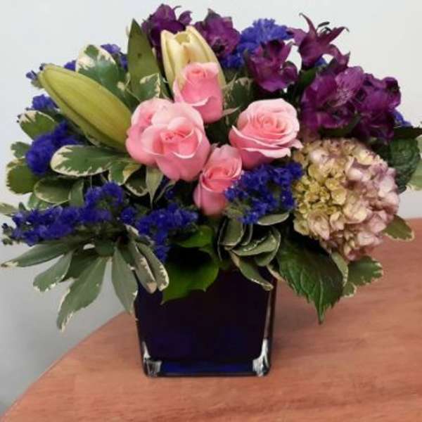 Pink roses and purple flowers in a dark glass vase