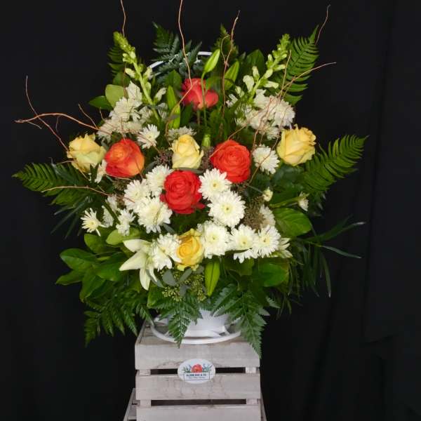 Large mixed bouquet of roses, lilies, and white daisies in a white container