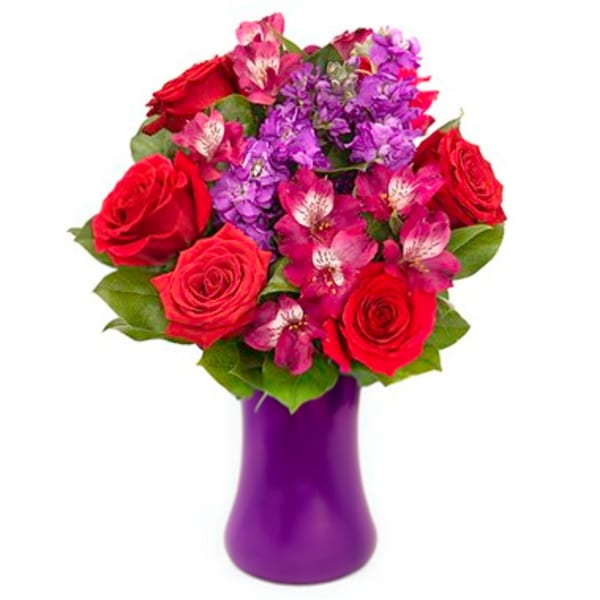 Red roses and purple flowers in a purple vase