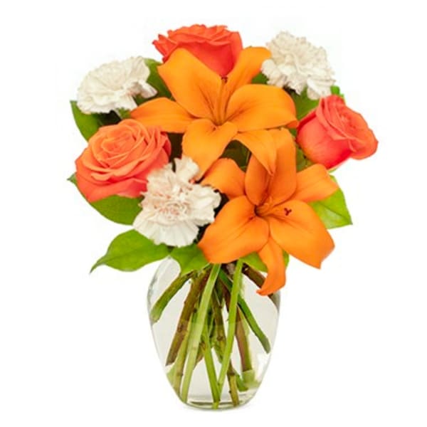 Orange lilies and roses in a clear glass vase with white carnations